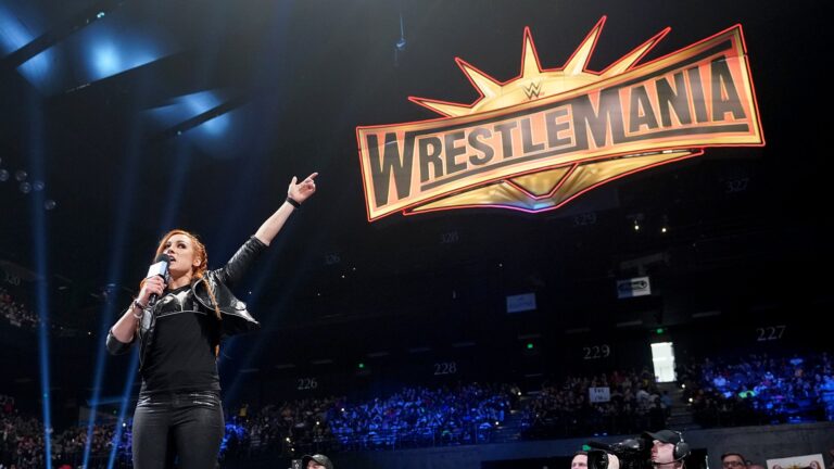 Becky Lynch apontando para o grande logo da Wrestlemania